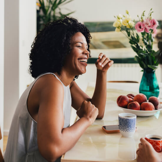 smiling woman at table with coffee and phone