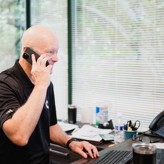 Craft team member smiling while working at his desk and talking on the phone