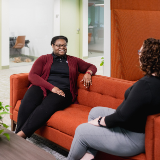 Two Craft team members talking together on a couch and smiling