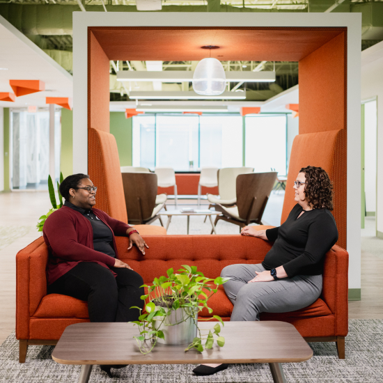 Two Craft team members talking together on a couch and smiling