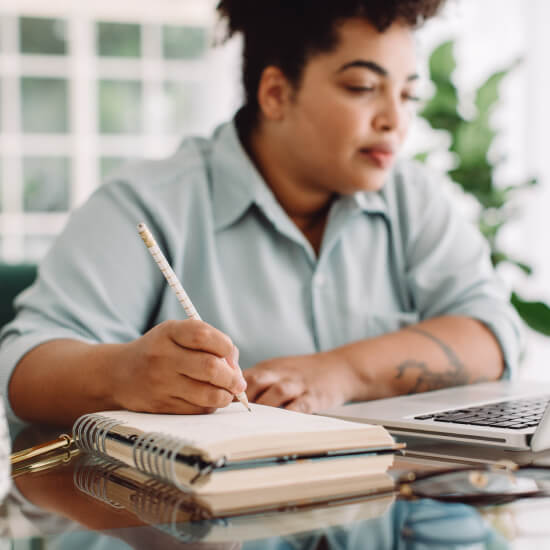 woman writing in a notebook at desk