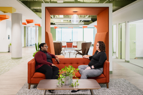 Two Craft team members talking together on a couch and smiling